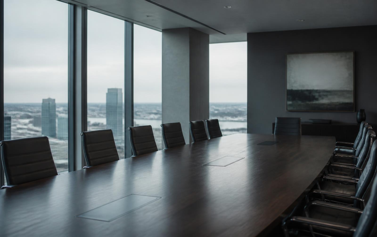 Empty boardroom at dawn with a long table and city view